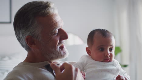 Hispanic-grandfather-holding-his-baby-grandson,-head-and-shoulders,-close-up