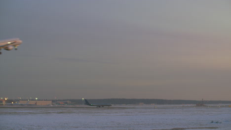 Flugzeug-Startet-Am-Winterabend-Mit-Blick-Auf-Den-Flughafen