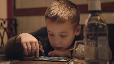 Niño-Aburrido-Usando-Un-Teléfono-Inteligente-En-La-Cafetería