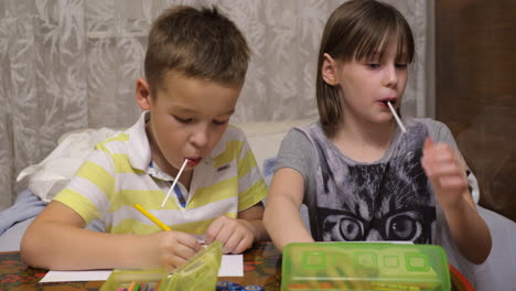 Boy-and-girl-with-lollipops-drawing-with-colour-pencils-at-home