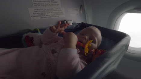 Active-baby-girl-flying-by-plane-in-special-bassinet