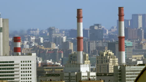 Cityscape-with-factory-pipes-in-foreground