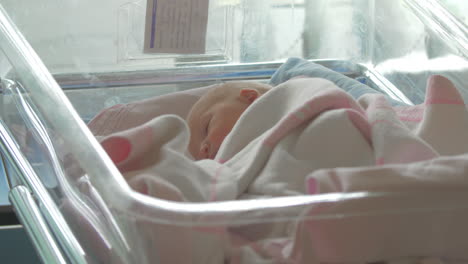 A-newborn-baby-girl-lying-awake-in-a-hospital-baby-cart