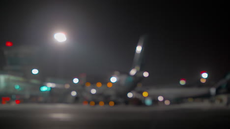 Blurred-airplane-at-the-airport-terminal-at-night