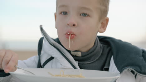 Young-boy-eating-pasta-outside