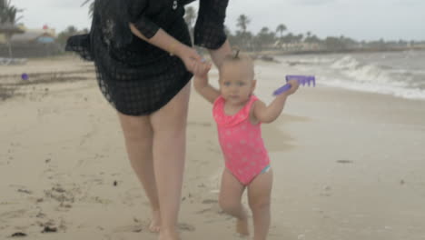 Mum-with-baby-daughter-walking-barefoot-on-the-beach