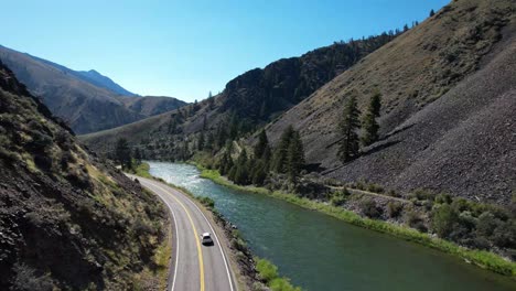 Car-driving-road-along-Snake-River-in-Idaho--aerial-follow-behind