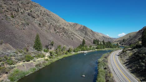 Snake-River-Idaho-with-two-lane-road-on-river-bank-and-car-driving-by--aerial