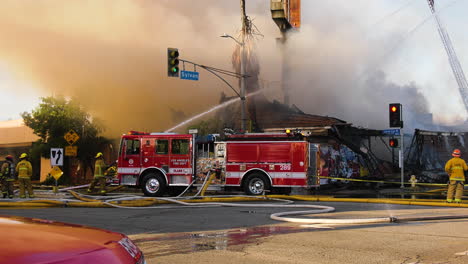 Feuerwehrauto-Und-Feuerwehrleute-Löschen-Ein-Brennendes-Gebäude,-Sonniger-Tag-In-Los-Angeles