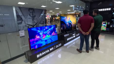 POV-SHOT,-CHROMA-SHOWROOM-IN-MALL-TWO-MEN-VIEWING-PERFORMANCE-OF-SONY-BRVIA-XR-OLED-TV-AND-PURCHASING