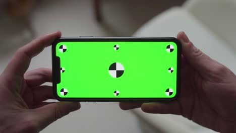 hands-holding-smartphone-with-green-screen-display-and-tracking-markers,-changing-orientation-from-portrait-to-landscape-and-back-to-portrait-again