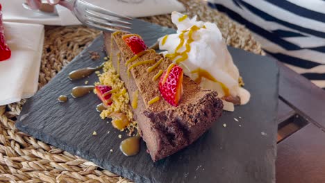 Woman-eating-chocolate-cake-with-strawberries-and-ice-cream-in-a-restaurant