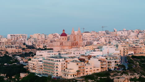 Vista-Aérea-Alrededor-De-La-Iglesia-Parroquial-De-Mellieha,-Colorida-Puesta-De-Sol-En-Malta