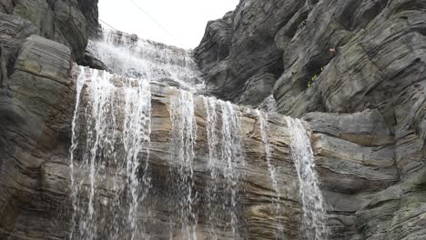 Waterfall-with-water-falling-down-the-rocky-cliff-slow-motion-static-shot,-Singapore
