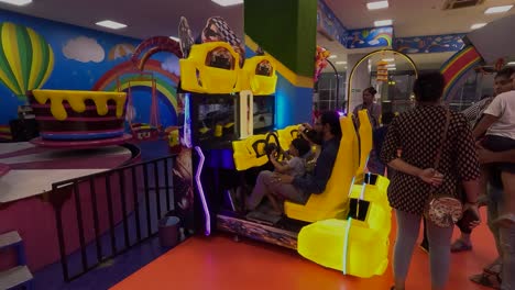 POV-SHOT-Parents-playing-a-car-game-with-their-child-in-Crazy-World-inside-the-mall