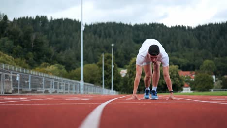 Sportlicher-Männlicher-Junger-Läufer,-Der-An-Der-Position-Auf-Der-Laufstrecke-Startet