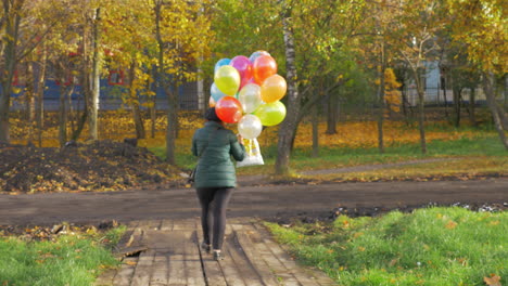Eine-Zeitlupe-Einer-Frau,-Die-An-Einem-Schönen-Herbsttag-Mit-Luftballons-Läuft