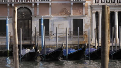 Empty-black-gondolas-swaying-on-a-pier-close-to-the-beautiful-white-facade