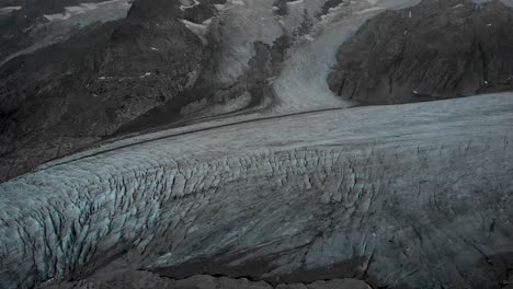 Aerial-view-of-the-Gauli-glacier-in-the-Bernese-Oberland-region-of-the-Swiss-Alps-with-a-panning-view-from-the-crevasses-at-the-glaciers-end-towards-the-mountain-peaks