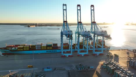 Sonnenaufgang-Im-Hafen-Von-Virginia,-Norfolk:-Großes-Maersk-Containerschiff-Mit-Hoch-Aufragenden-Kränen-Angedockt