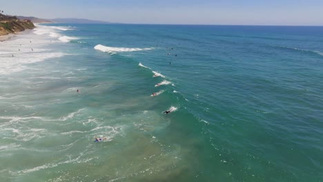 Surfers-Riding-Waves-In-Del-Mar-Beach-In-San-Diego,-California---aerial-drone-shot