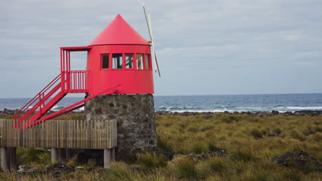 Static-close-up-shot-of-small-red-windmill-located-at-the-rocky-coastline