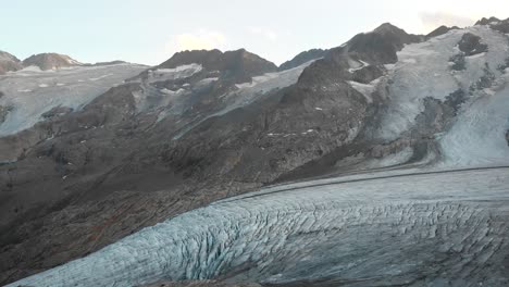 Aerial-flight-next-to-the-Gauli-glacier-in-the-Bernese-Oberland-region-of-the-Swiss-Alps-with-a-panning-view-over-the-glacier's-crevasses-at-sunset