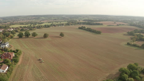 High-wide-aerial-shot-over-a-tractor-ploughing-a-large-field