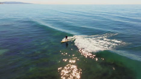 Surfer-Riding-Blue-Ocean-Wave-In-San-Diego,-California,-USA---aerial-drone-shot
