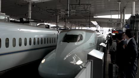 N700-Series-Shinkansen-Bullet-Train-Arriving-At-Platform-At-Hiroshima-Station-Platform-With-Commuter-Waiting-Behind-Safety-Railing