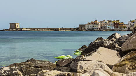 Timelapse-shot-of-ruins-of-a-historic-building-along-the-sea-shore-in-Trapani,-Sicily,-Italy-on-a-sunny-day