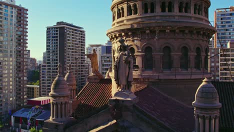 Aerial-view-circling-Sacramentino-church-rooftop-statues-and-ornate-bell-tower-with-surrounding-high-rise-urban-city-landscape