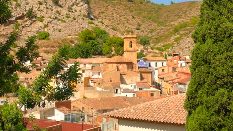 High-angle-shot-over-an-old-typical-Spanish-quaint-village-with-church-tower-in-distance-in-Borriol,-Spain-on-a-sunny-day