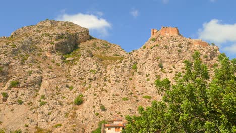 Pan-shot-of-large-rock-formation-giving-detail-to-the-castle-ruins-of-an-ancient-picturesque-village,-Borriol,-Spain