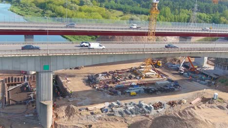 Industrial-cranes-and-construction-site-of-A1-bridge-over-Neris-river,-aerial-view