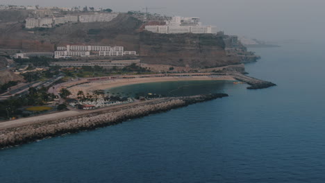 Mogan,-Amadores-Beach,-Gran-Canaria:-aerial-shot-in-orbit-over-the-famous-beach-and-spotting-the-hotels-in-the-area