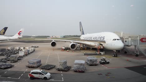 Remolcador-De-Equipaje-Moviendo-Contenedores-De-Carga-Junto-Al-A380-De-Singapore-Airlines-Estacionado-En-El-Aeropuerto-De-Changi