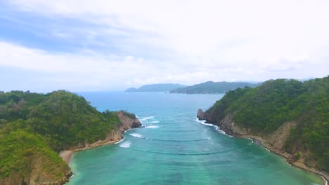 Drone-flying-up-over-water-between-two-green-islands-in-Costa-Rica's-Tortuga-Island-Archipelago