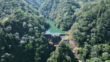 Aerial-backwards-shot-of-Tireo-Dam-in-deep-jungle-during-sunny-day-on-Dominican-Republic-Island---Panorama-view