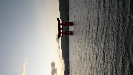 Silhouette-Of-Itsukushima-Floating-Grand-Torii-Gate-During-Sunset-Flares-In-Background