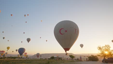 Hot-air-balloons-descend-to-land-in-morning-sun-kissed-field