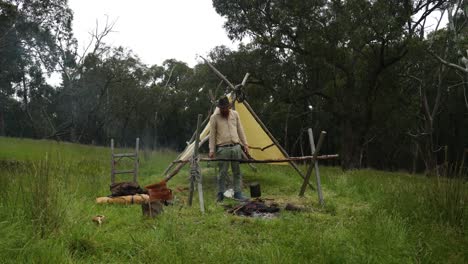 A-bush-settler-cooks-over-a-fire-with-a-billy-at-a-hisotorical-pioneer-camp