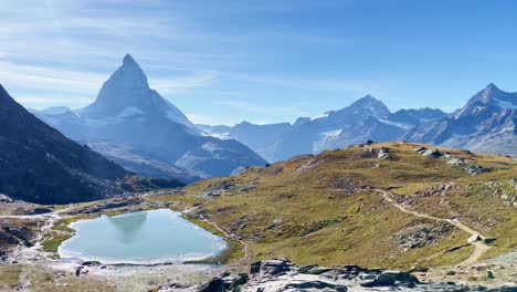 Mountain-Freedom:-Matterhorn-Mountain-Landscape-Near-Rotenboden-and-Gornergart,-Switzerland,-Europe-|-Movement-Over-Rough-Landscape-Near-Rock-Sculptures-Above-Travel-Couple-in-Distance,-Hiking