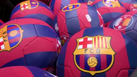 Balones-De-Fútbol-Decorados-Con-Los-Colores-Del-Equipo-De-Fútbol-De-Barcelona-Y-Su-Insignia-A-La-Venta-En-Una-Tienda-Oficial-De-Productos