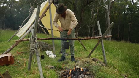 Australian-bushman-hangs-up-a-billy-over-a-campfire-in-the-bush-by-his-historical-hut
