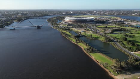 Drone-establishing-shot-of-Swan-River-with-modern-Matagarup-Bridge-and-Optus-Stadium-in-Perth-City-during-golden-hour