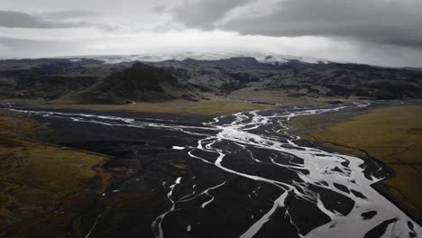 Cinematic-aerial-glacial-rivers-flowing-through-black-volcanic-scenery,-Iceland-landscape