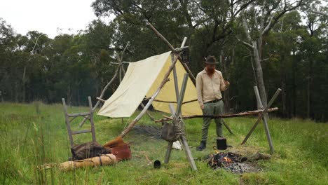 Australian-bushman-smokes-a-pipe-by-a-historical-looking-pioneer-camp