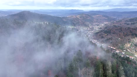 Aerial-orbiting-over-a-moody-dark-and-cold-forest-of-Plainfaing-in-Vosges-with-fast-moving-clouds-in-4K
