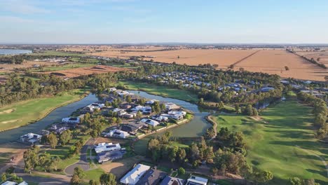 Aerial-view-of-water-hazards-houses-and-fairways-of-golf-course-with-wheat-fields-beyond-near-Yarrawonga